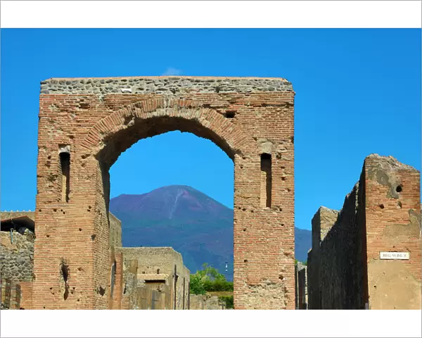 Ruined archway in the ancient Roman city of Pompeii and Mount Vesuvius, Italy
