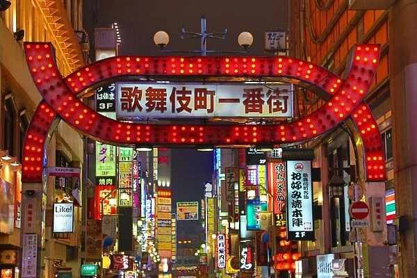 Night street scene of illuminated signs and lights of shops in Shinjuku, Tokyo, Japan