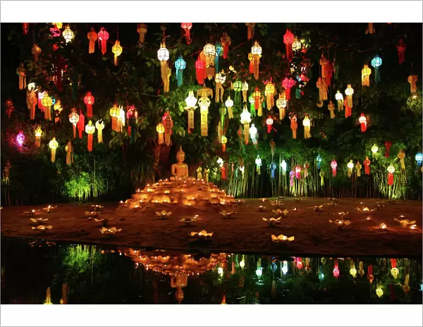 Lanterns and candles reflected in a pool with a Buddha stature for the Loy Krathong Festival at Wat Phan Tao Temple in Chiang Mai, Thailand