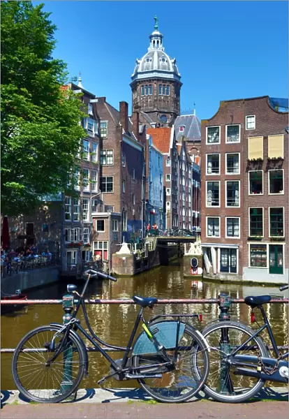 Bicycles on a canal bridge and the Basilica of Saint Nicholas in Amsterdam, Holland
