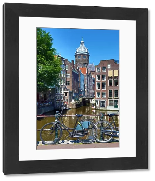 Bicycles on a canal bridge and the Basilica of Saint Nicholas in Amsterdam, Holland