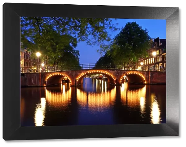 Illuminated canal bridge at night on the canal between Prinsengracht and Brouwersgracht