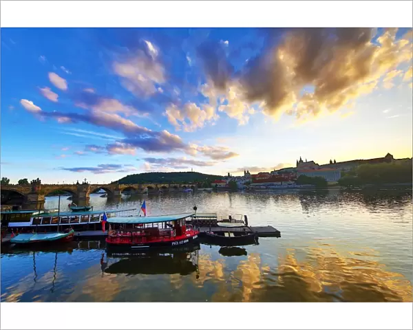 Charles Bridge over the Vltava River and boats at sunset in Prague, Czech Republic