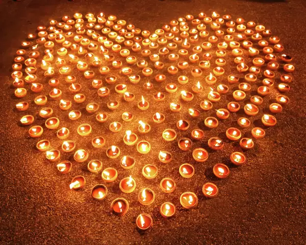 Love heart shape made out of burning candles and light