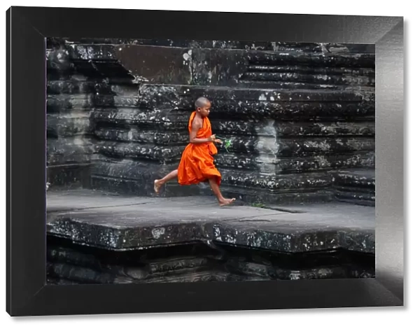 Young Buddhist monk running at Angkor Wat Temple, Cambodia