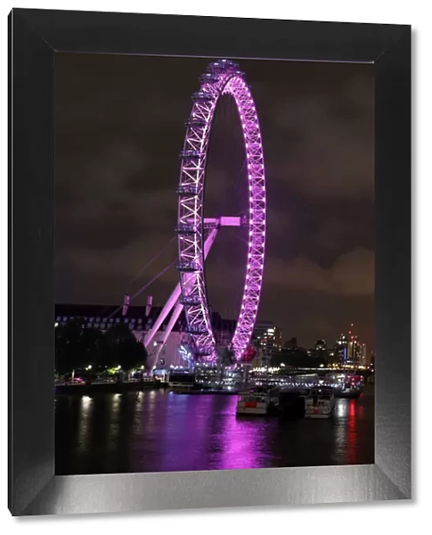 London Eye illuminated pink and the River Thames, London