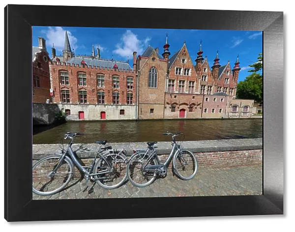 Bicycles leaning against a canal wall with medievel buildings, Bruges, Belgium