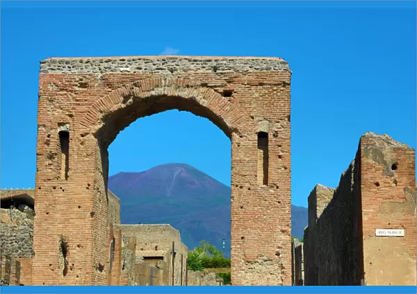 Ruined archway in the ancient Roman city of Pompeii and Mount Vesuvius, Italy