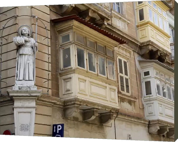 Statue of St. Francis and covered wooden balconies in the street in Valletta, Malta