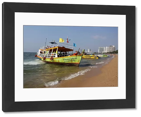 Beach scene with a tourist ferry boat on the seafront of Pattaya, Thailand