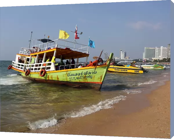 Beach scene with a tourist ferry boat on the seafront of Pattaya, Thailand