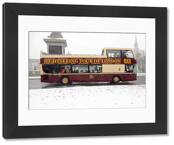 Snow and tourists on sightseeing bus in Trafalgar Square, London