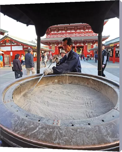 Man cleaning ashes in an incense burnder at the Sensoji Asakusa Kannon Temple, Tokyo, Japan