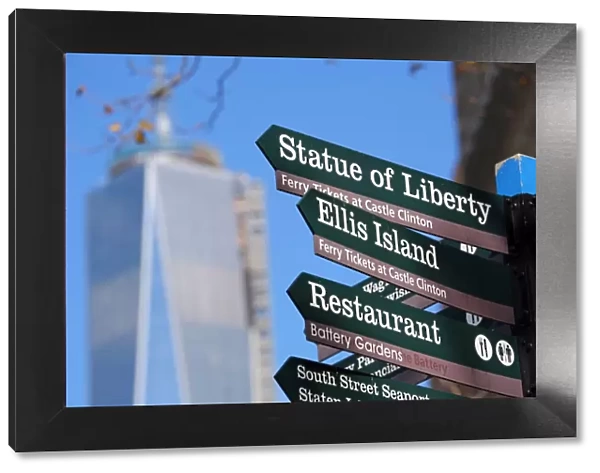 Direction signs to the Statue of Liberty and Ellis Island with One Trade Center ( 1 WTC ) in the background, New York. America