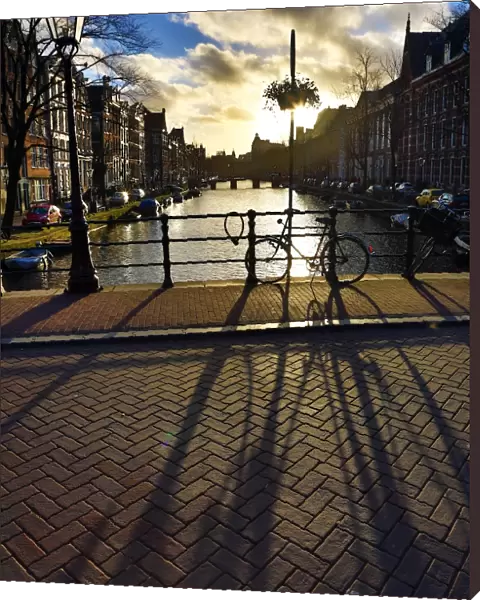 Silhouette of a parked bicycle and its shadow on a bridge over a canal in Amsterdam, Holland