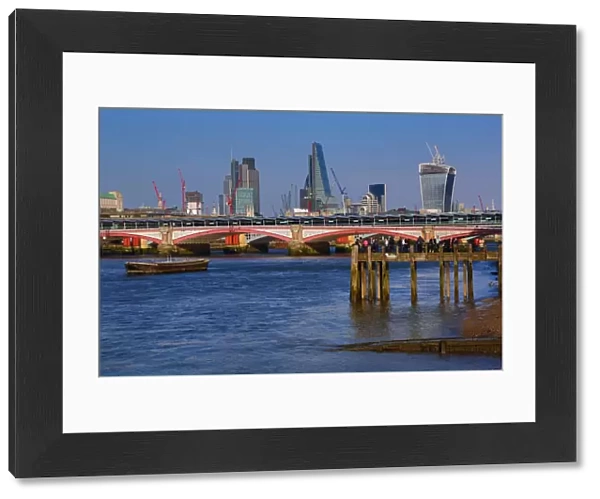 Wooden pier at Oxo Tower Wharf on the River Thames with Blackfriars Bridge and the City of London skyline in London, England