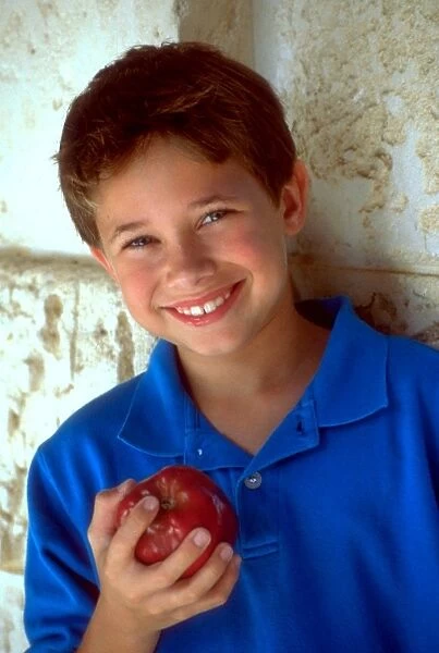 Boy holding apple. Boy eating red apple