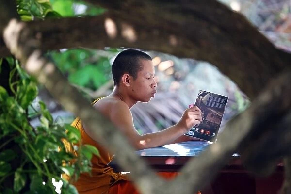 Buddhist monk reading a book at Vat Sop Sickharam temple, Luang Prabang, Laos