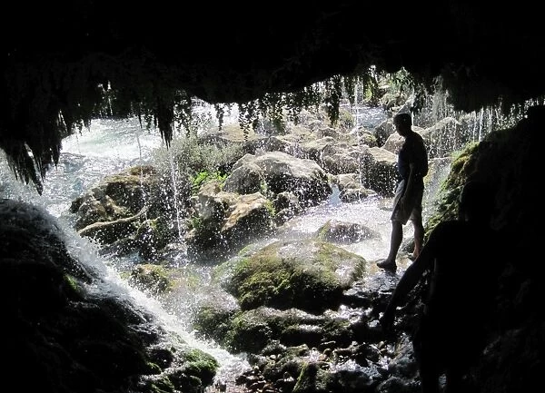 Cave in Croatia. Silhouette of cave entrance and waterfall in Croatia
