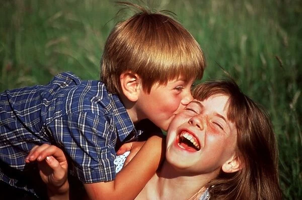 Children kissing. Boy and girl kissing and laughing outdoors