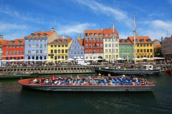 Coloured houses and a tourist sightseeing tour boat at Nyhavn Quay in Copenhagen, Denmark