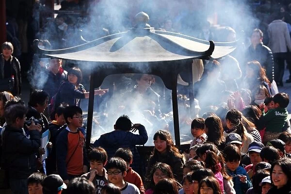Crowds of people burning incense at the Shinto Shrine at Senso-Ji Bhuddist Temple in Asakusa in Tokyo, Japan