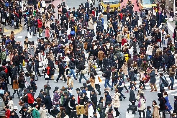 Crowds of people at rush hour crossing pedestrian crossings in Shibuya, Tokyo, Japan