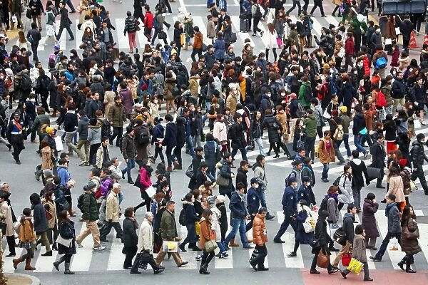 Crowds of people at rush hour crossing pedestrian crossings in Shibuya, Tokyo, Japan