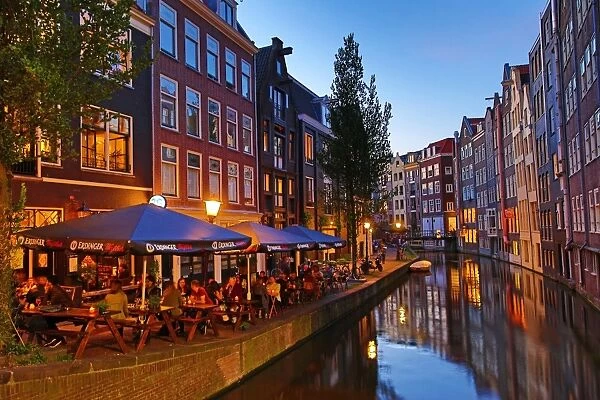 Houses and restaurants on the Oudezijds Achterburgwal canal at sunset in Amsterdam