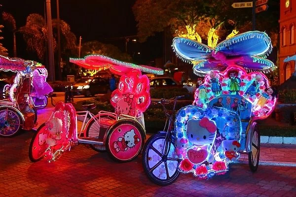 Illuminated decorated kitsch cycle trishaw rickshaw with soft toys at night in Malacca, Malaysia