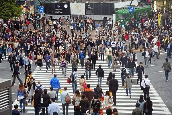 Japanese street scene showing crowds of people crossing the street on a pedestrian crossing in Shibuya, Tokyo, Japan