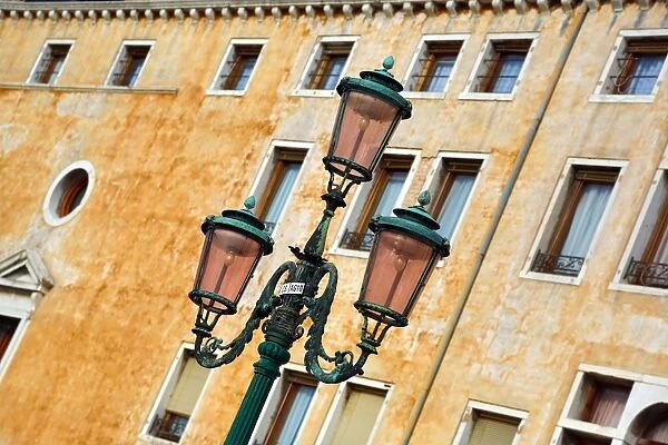 Lamp post and the wall of a building with windows in Venice, Italy