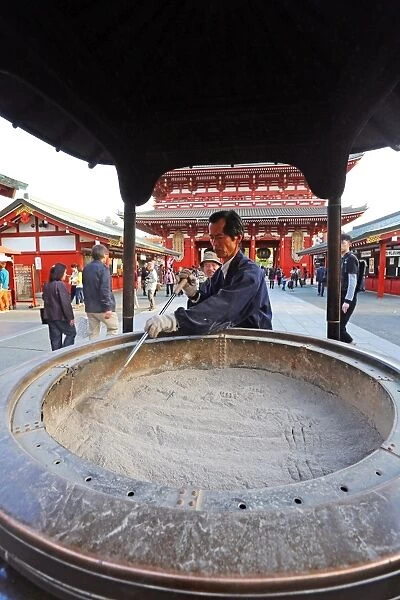 Man cleaning ashes in an incense burnder at the Sensoji Asakusa Kannon Temple, Tokyo, Japan