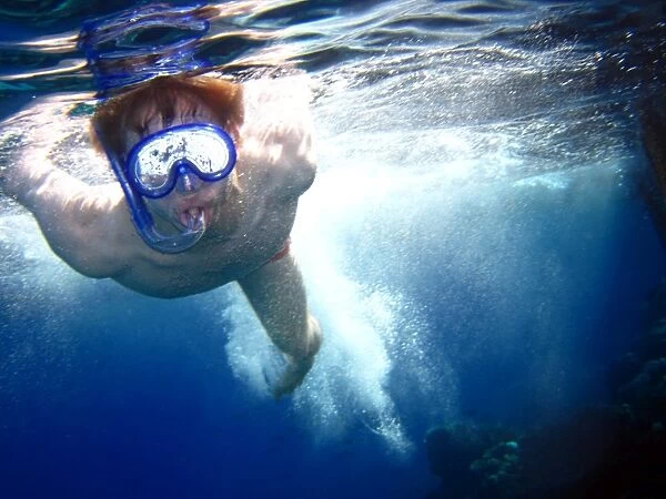 Man swimming on summer holiday diving wearing snorkelling mask
