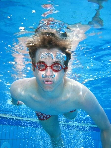Man swimming underwater in a swimming pool wearing goggles