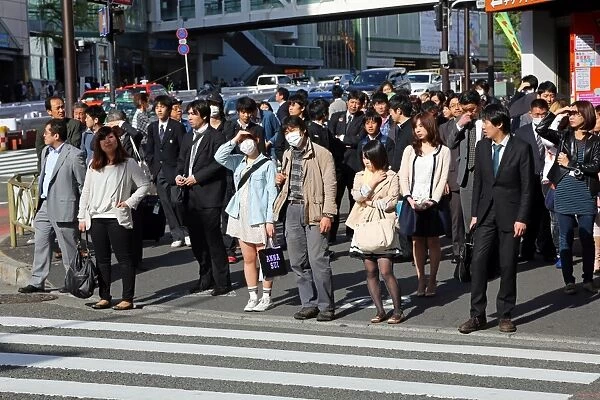 People waiting at a pedestrain crossing to cross a road in Shinjuku, Tokyo, Japan
