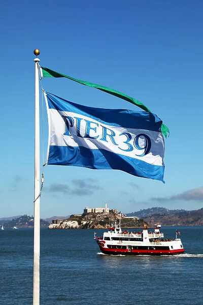 Pier 39 flag, sightseeing boat and Alcatraz prison island in San Franciso, California