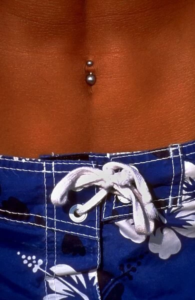 Pierced Navel. Stomach of man with pierced navel above shorts