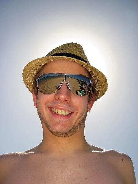Portrait of a smiling man on summer holiday wearing a straw hat