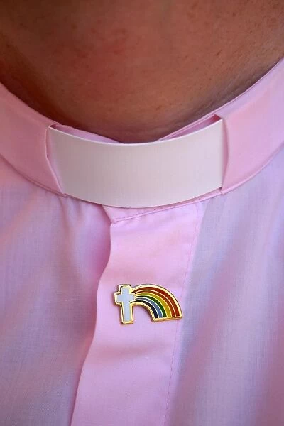 Rainbow Cross. Gay clergy with pink dog collar and rainbow badge