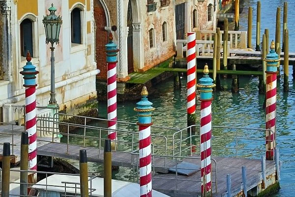 Red and white striped gondola mooring posts on the Grand Canal, in Venice, Italy