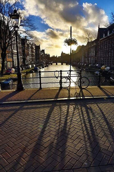 Silhouette of a parked bicycle and its shadow on a bridge over a canal in Amsterdam, Holland
