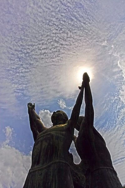 Silhouette of a statue of men reaching for the sky in Lumpini Park in Bangkok, Thailand