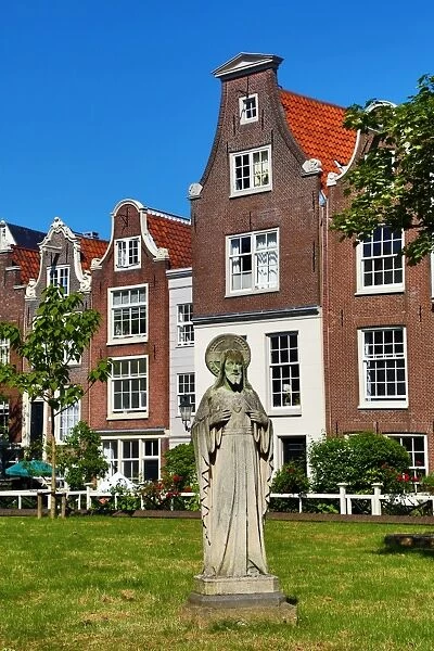 Statue of Jesus Christ and traditional Dutch houses in Begijnhof in Amsterdam, Holland