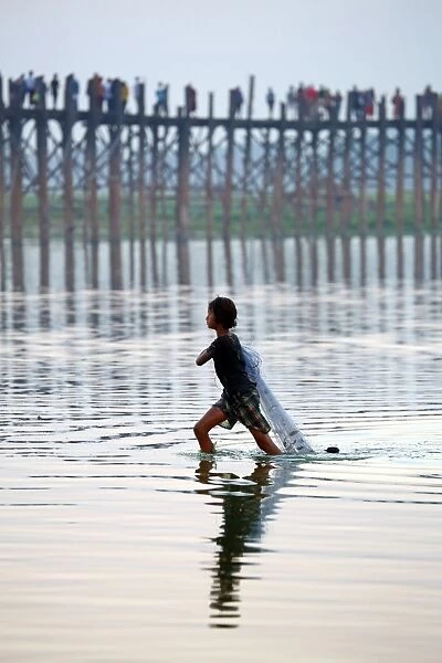 The U Bein Bridge with a fisherman walking across the Taungthaman Lake in Amarapura