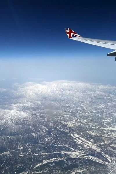 View out of an aircraft window with mountains and a plane wing
