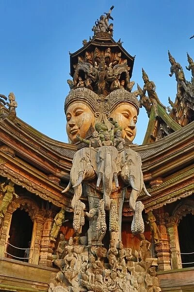 Wooden carving on the Sanctuary of Truth Temple, Prasat Sut Ja-Tum, Pattaya, Thailand showing a wood statue of faces and elephants