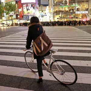 Japanese street scene showing crowds of people crossing the street and a cyclist on a pedestrian crossing in Shibuya, Tokyo, Japan