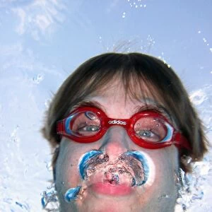 Man swimming underwater wearing goggles blowing bubbles