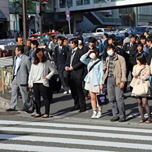 People waiting at a pedestrain crossing to cross a road in Shinjuku, Tokyo, Japan